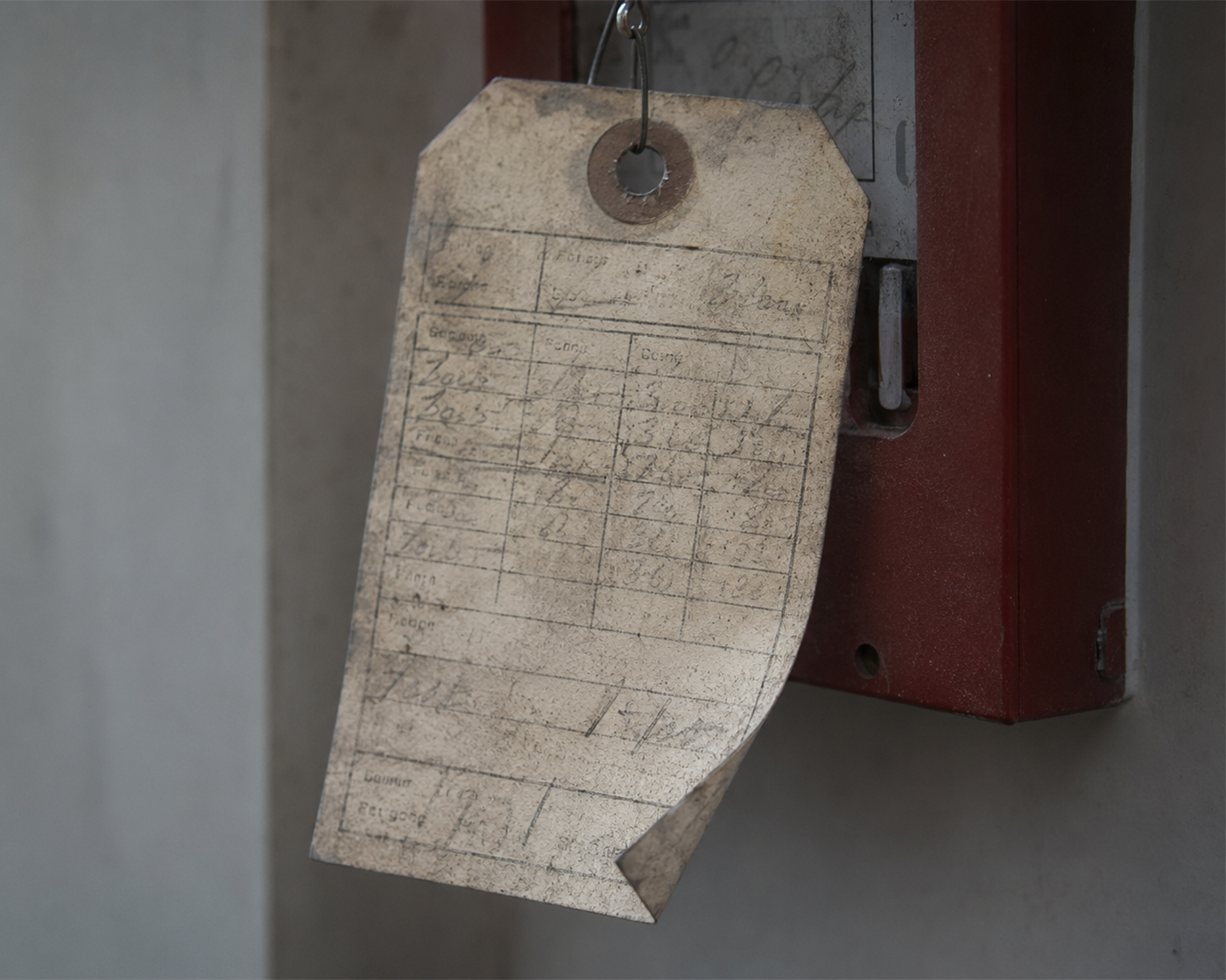 A neglected fire extinguisher with a grimy, half-illegible paper inspection tag